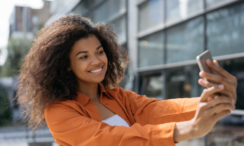 Una joven negra tomando un selfie en su teléfono inteligente.
