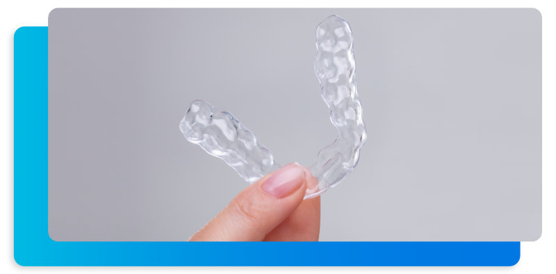 Abrazaderas transparentes sujetadas con dos dedos frente a un fondo gris.