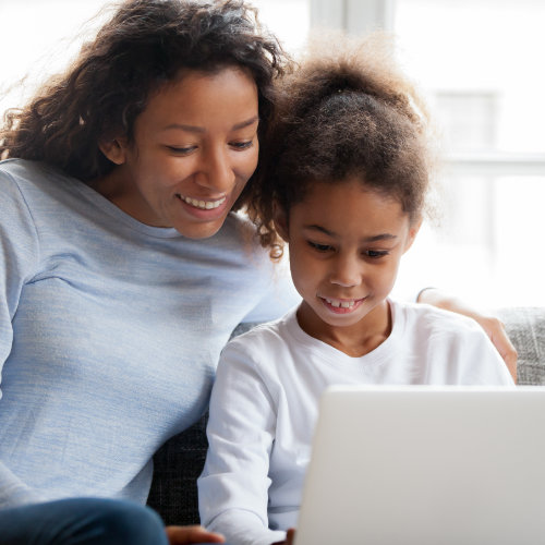 Mujeres con hija buscando opciones financieras para alineadores transparentes en una computadora portátil.